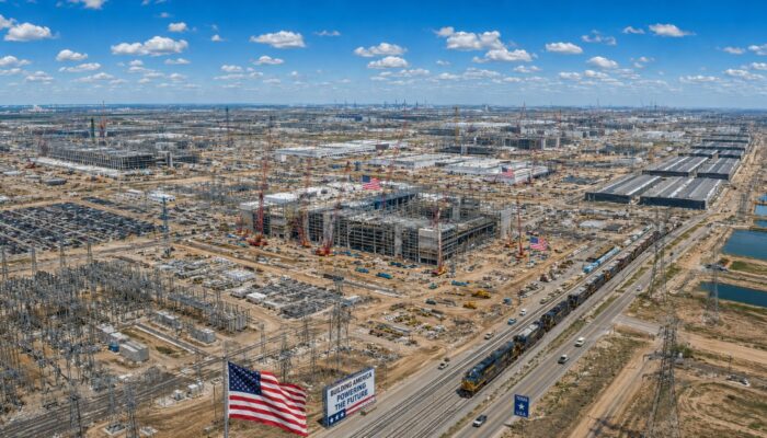 Massive AI infrastructure construction in the United States showing data centers, electrical substations, transmission lines, and semiconductor manufacturing facilities supporting the AI arms race.